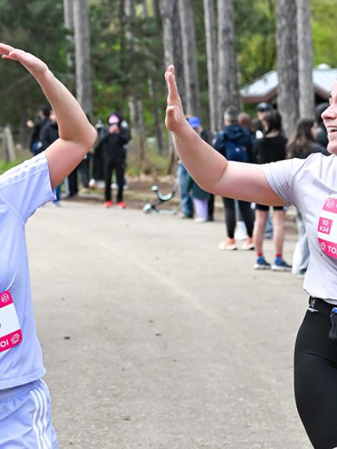 Deux coureuses se tapent dans les mains sur la ligne d'arrivée du 10 km de la course courir pour toit