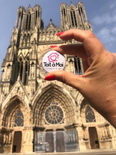 Un badge Toit à Moi devant la cathédrale de Reims