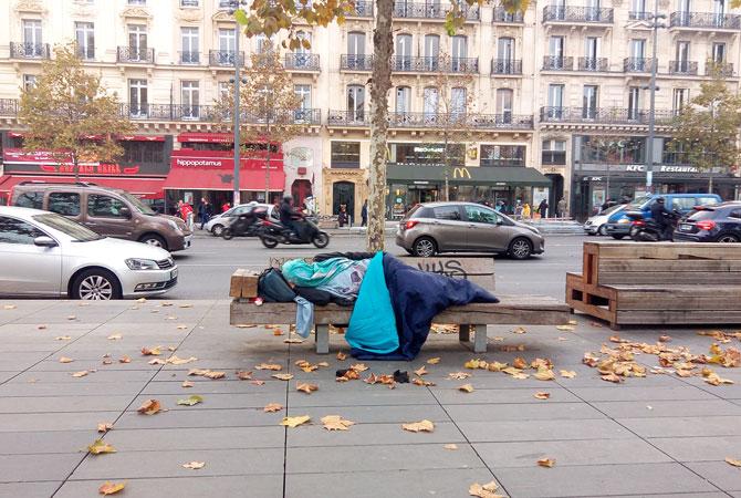 Une personne sans-abri dort sur un banc à Paris