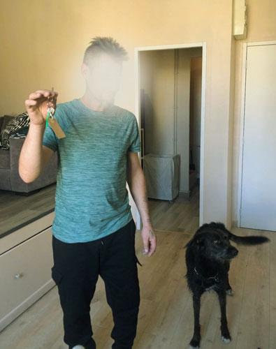 Pierre et sa chienne le jour de leur arrivée dans le logement-tremplin à Marseille Pierre (visage flouté) brandit les clés de son logement, à ses côtés se tient sa chienne au pelage noir