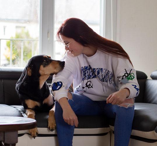 Romane et son chien, dans leur nouveau logement autonome Romane et son chien sont assis sur un canapé et échangent un regard complice