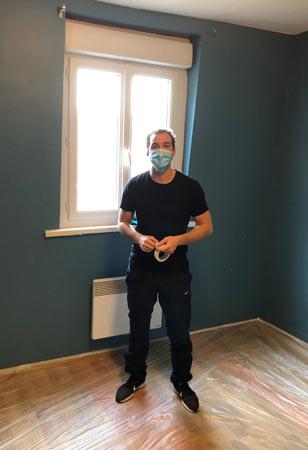 Un bénévole pose du scotch dans un appartement en rénovation
