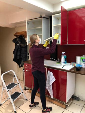 Une bénévole installe et lave les placards de la future cuisine d'un logement Toit à Moi
